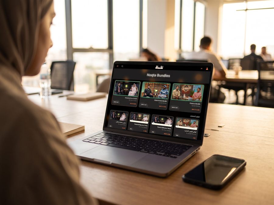 A bilingual course platform open on a laptop in a co-working space